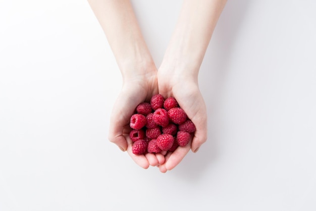 Gezond eten, diëten, vegetarisch eten en mensenconcept - close-up van vrouwenhanden die frambozen thuis houden