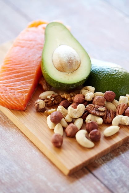 gezond eten, eiwitdieet en culinair concept - close-up van zalmfilets, avocado en noten op tafel