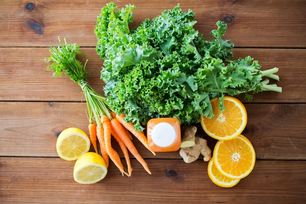 gezond eten, eten, diëten en vegetarisch concept - close-up van fles met wortelsap, fruit en groenten op houten tafel