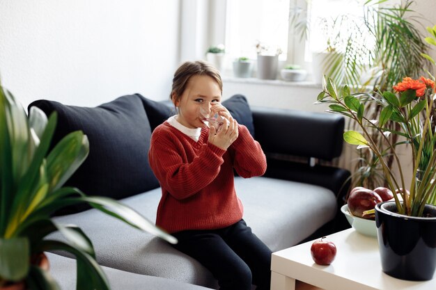 Gezond eten - kind houden en drinken van glas water, veel vers fruit op de tafel vooraan thuis, gezonde levensstijl concept