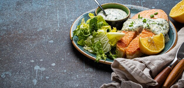 Gezond eten maaltijd gekookt gegrilde zalm steak met witte dille saus en groene salade bladeren