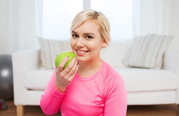 gezond eten, natuurvoeding, dieet en mensenconcept - gelukkige vrouw die thuis appel eet