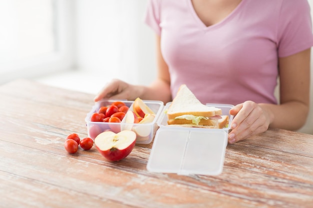 gezond eten, opslag, diëten en mensen concept - close-up van vrouw met voedsel in plastic container thuis keuken