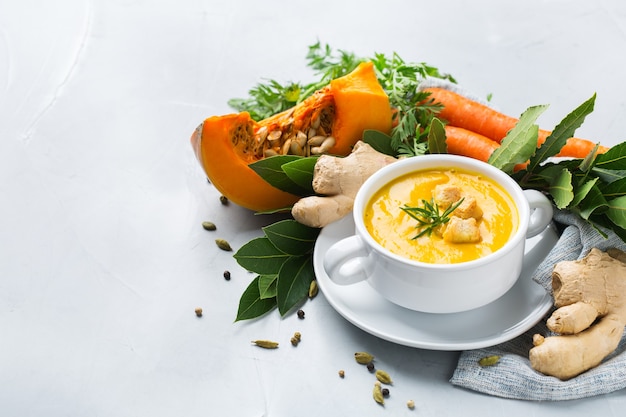 Gezond eten, schoon eten concept. Seizoensgebonden pittige herfstgroenten romige pompoen- en wortelsoep met ingrediënten op een tafel. Ruimte achtergrond kopiëren