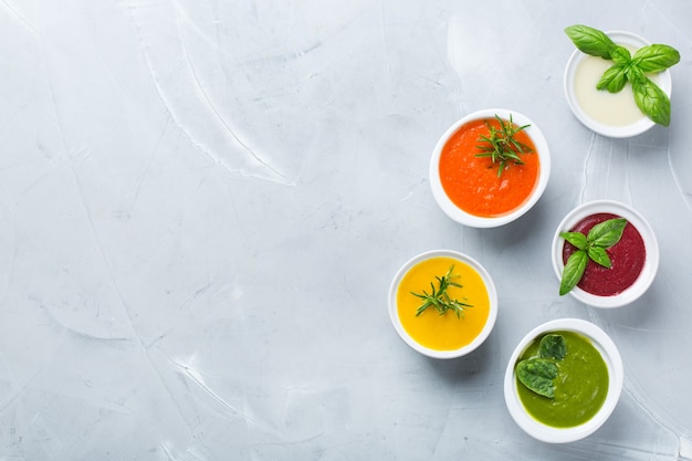 Gezond eten, schoon eten concept. Verscheidenheid aan kleurrijke seizoensgebonden herfstgroenten romige soepen met ingrediënten. Pompoen, broccoli, wortel, rode biet, aardappel, tomatenspinazie. Plat leggen, ruimte kopiëren