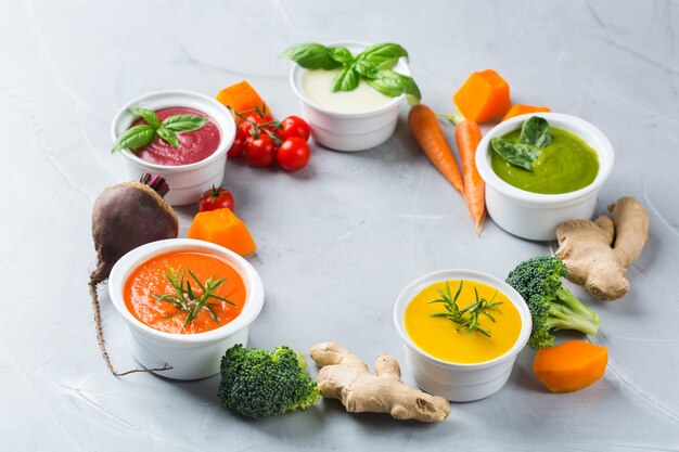 Gezond eten, schoon eten concept. verscheidenheid aan kleurrijke seizoensgebonden herfstgroenten romige soepen met ingrediënten. pompoen, broccoli, wortel, rode biet, aardappel, tomatenspinazie