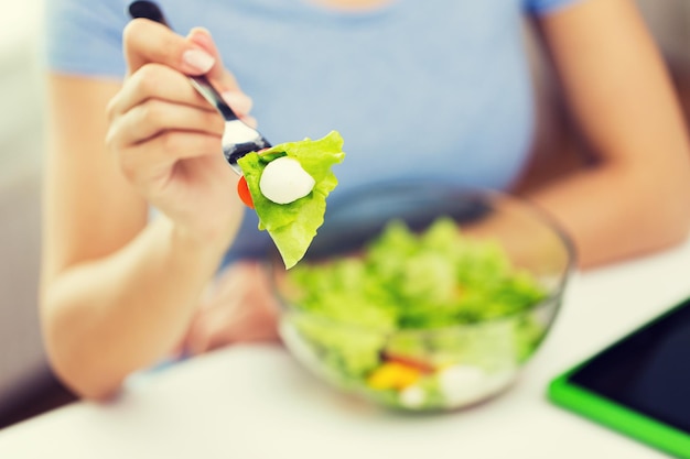 gezond eten, voeding, voeding en mensen concept - close-up van jonge vrouw die groentesalade eet met vork thuis