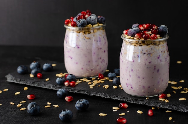 Gezond fitness voedselconcept. Potten yoghurt met bosbessen, granaatappelzaden en haver