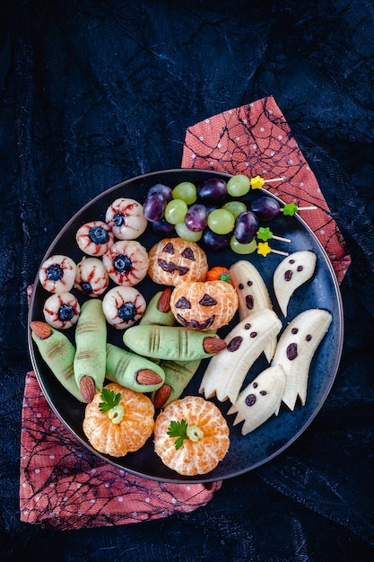 Gezond fruit Halloween-traktaties. Banana Ghosts, Clementine Orange Pumpkins, Lychee Eyes en Green Witch Fingers Cookies