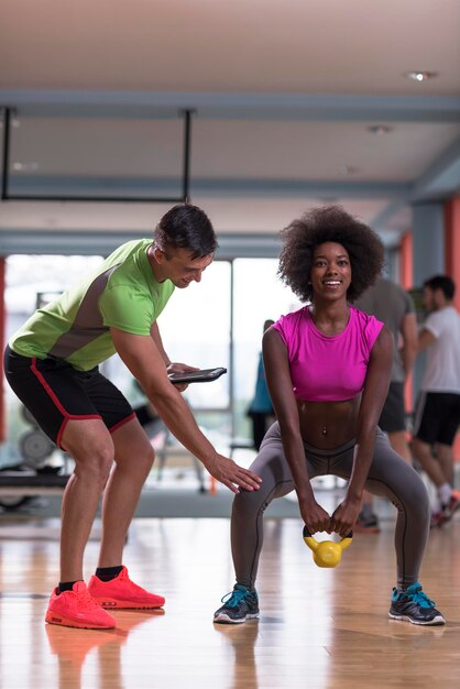 Foto gezond jong koppel in crossfit gym gewichten training met personal trainer