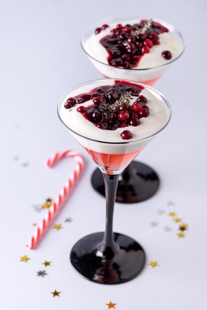 Gezond kerstdessert met geleiyoghurt en bessen in glazen op blauwe achtergrond Holiday