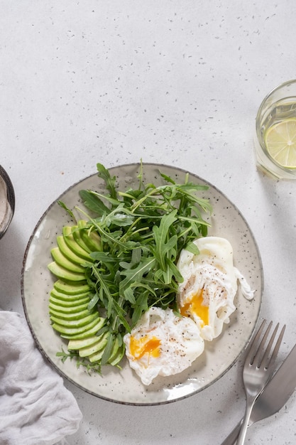 Gezond koolhydraatarm ontbijt gepocheerde eieren met avocado en rucola