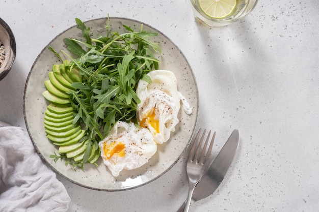 Gezond koolhydraatarm ontbijt gepocheerde eieren met avocado en rucola