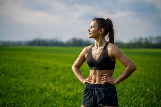 Gezond levensstijlconcept. Jonge aantrekkelijke vrouw in sportkleding strekt haar hand uit voordat ze bij zonsopgang op de natuur traint. Spier opwarming