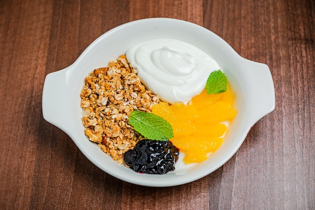 Gezond ontbijt, bestaande uit granola met griekse yoghurt en verse sinaasappel