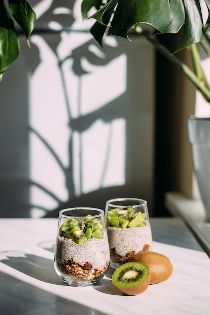 Gezond ontbijt. chia pudding met kiwi en granola in glas op witte achtergrond