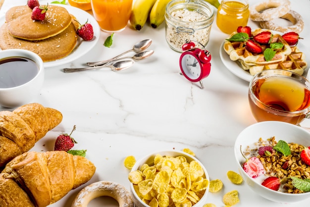 Gezond ontbijt eten concept verschillende ochtend eten - pannenkoeken wafels croissant havermout sandwich en muesli met yoghurt fruit bessen koffie thee sinaasappelsap witte achtergrond