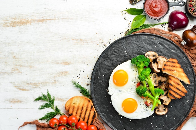 Gezond ontbijt Gebakken ei met broccoli champignons en brood Op een zwarte stenen plaat Bovenaanzicht