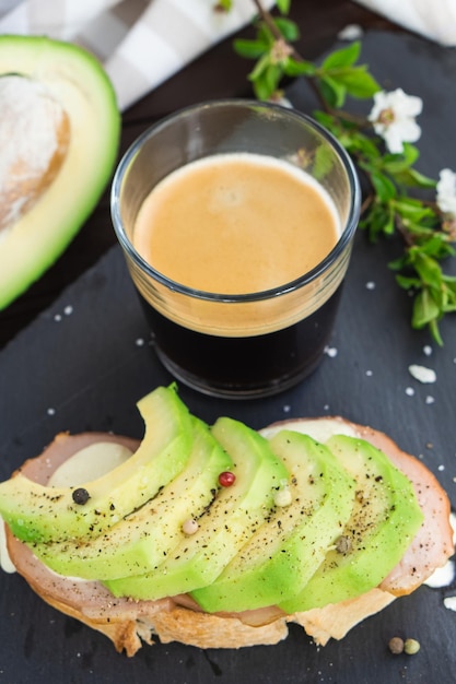Gezond ontbijt Geroosterd graanbrood met vers gesneden avocado ham kaas en kopje koffie