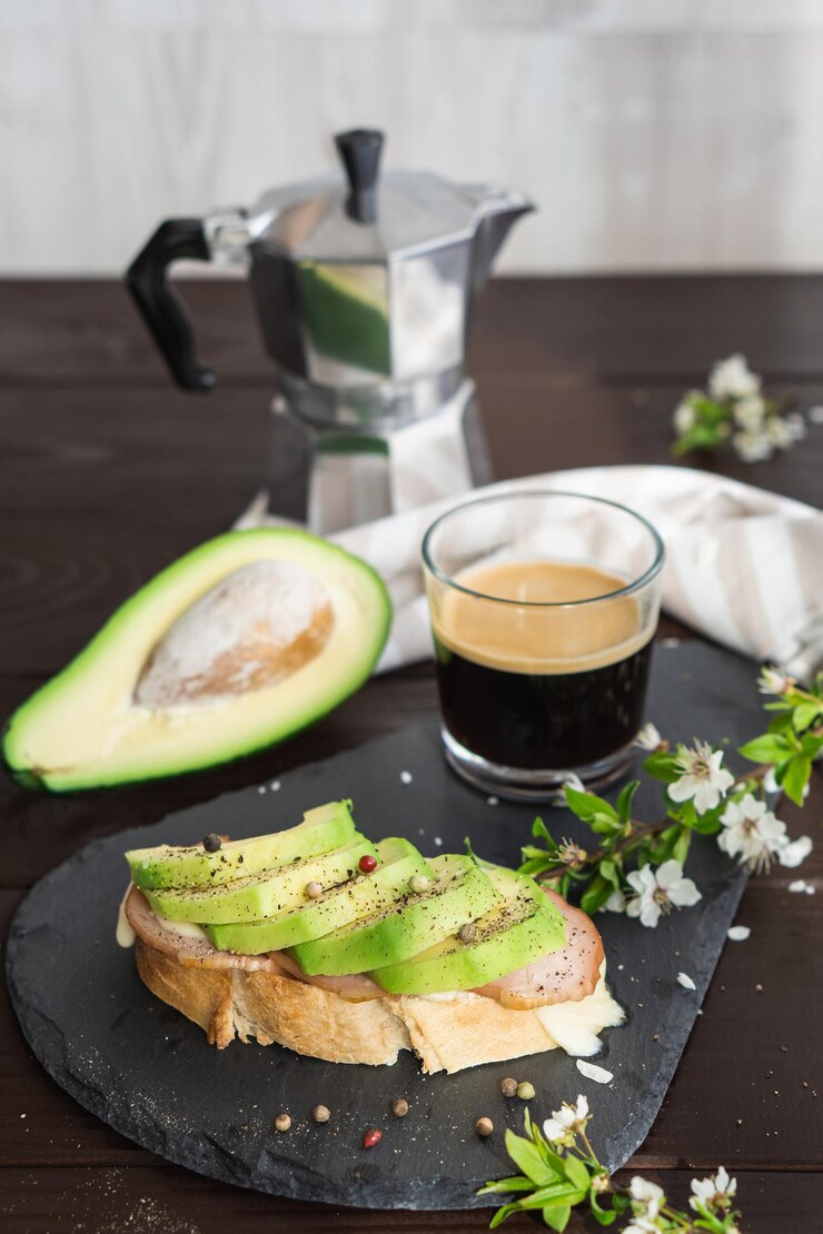 Gezond ontbijt. Geroosterd granenbrood met vers gesneden avocado, ham, kaas en kopje koffie