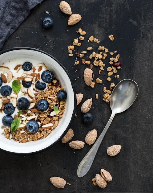 Gezond ontbijt Havergranola met verse bosbessen, amandelyoghurt en munt in een rustieke metalen kom