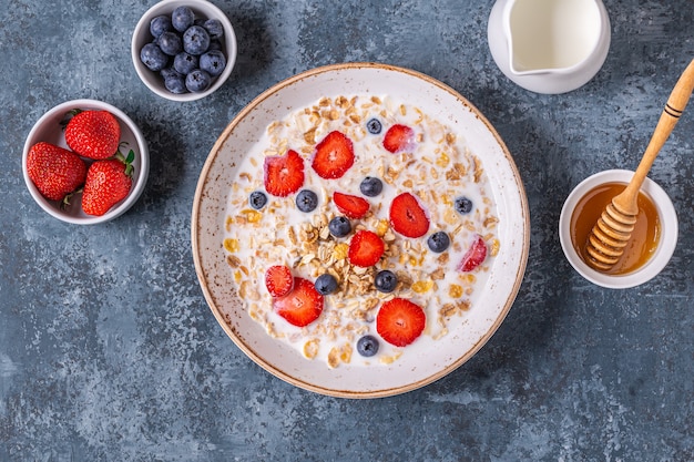 Gezond ontbijt, kom met havergranola, melk en bessen, bovenaanzicht.