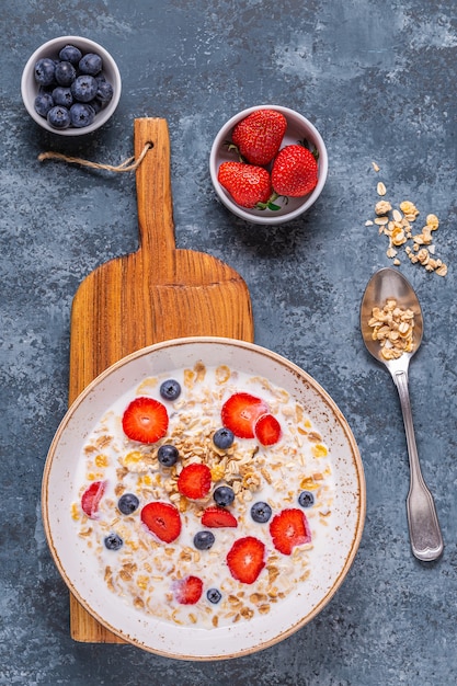 Gezond ontbijt, kom met havergranola, melk en bessen, bovenaanzicht.