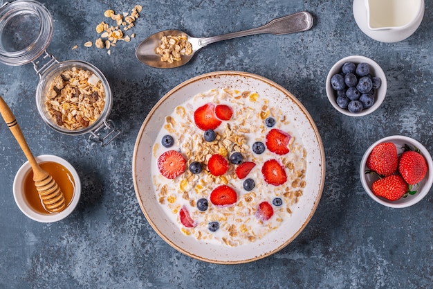 Gezond ontbijt, kom met havergranola, melk en bessen, bovenaanzicht.