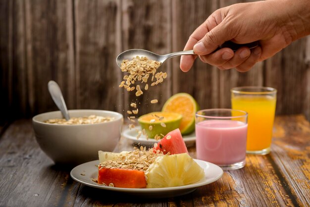 Gezond ontbijt met fruit, haver en yoghurt op houten tafel.