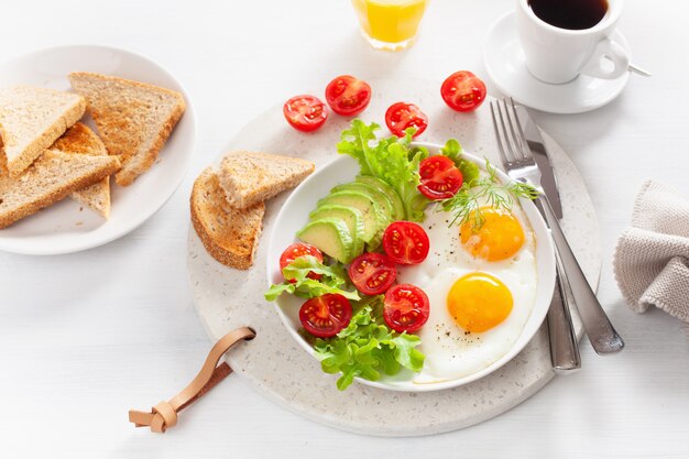 Gezond ontbijt met gebakken eieren, avocado, tomaat, toast en koffie