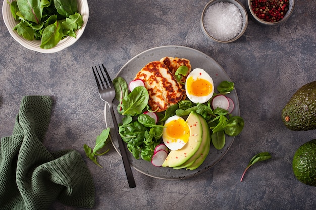 Gezond ontbijt met keto paleo-dieet: gekookt ei, avocado, halloumi-kaas, slablaadjes