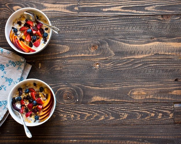 Foto gezond ontbijt met melk, muesli en fruit, op een houten achtergrond.