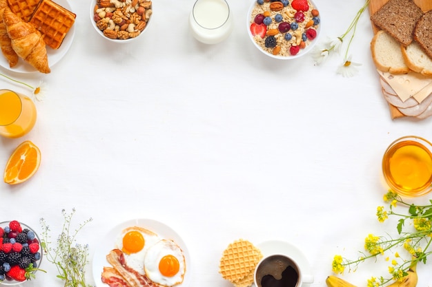 Gezond ontbijt met muesli, fruit, bessen, noten, koffie, eieren, honing op witte achtergrond