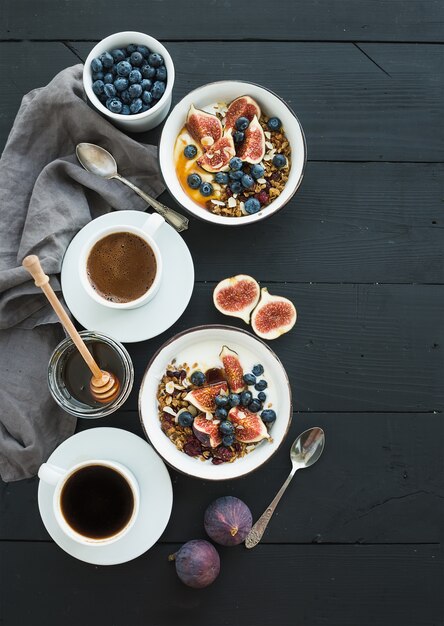 Gezond ontbijt set. Kommen havermuesola met yoghurt, verse bosbessen en vijgen, koffie en honing