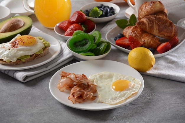 Gezond ontbijt Toast met avocado en ei, bacon en eieren vers en gedroogd fruit vers sap