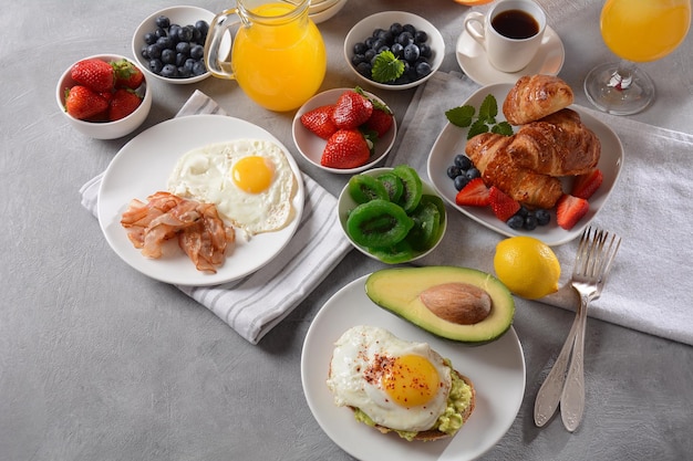 Gezond ontbijt Toast met avocado en ei, bacon en eieren vers en gedroogd fruit vers sap