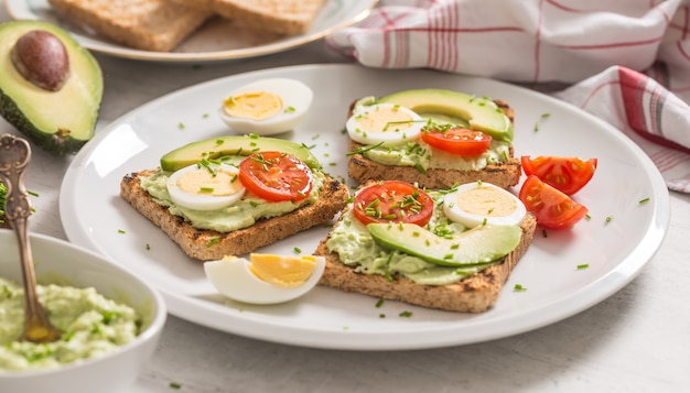 Gezond ontbijt van toast met avocado spread guacamole ei tomaat en bieslook.