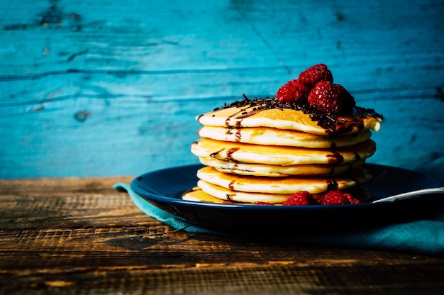 Gezond ontbijt zelfgemaakte pannenkoeken met verse frambozen en chocoladesaus op een oude houten tafel kopie ruimte