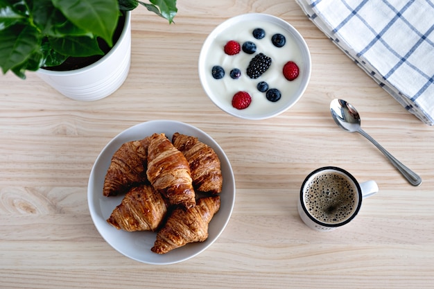 Gezond ontbijtconcept met de rode vruchten van de koffieyoghurt en croissant op wooddenlijst