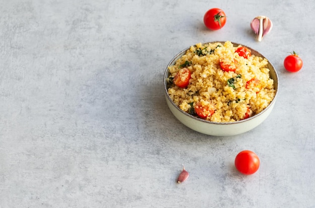 Foto gezond quinoa recept met tomaat, spinazie en knoflook. horizontaal, op een grijze achtergrond met kopieerruimte.