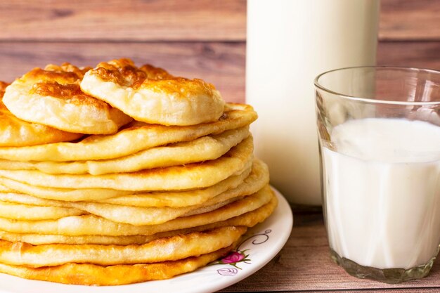 Gezond rustiek voedsel melk in een fles een glas en warme broodjes voor het ontbijt tarwemeelcakes houten achtergrond