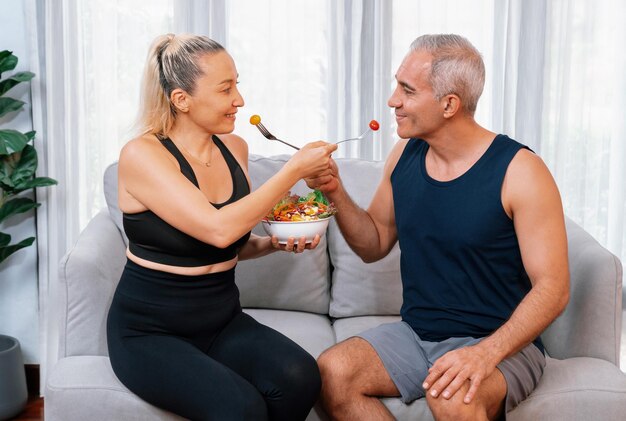 Gezond senior koppel in sportkleding met een kom fruit en groente Gezonde keukenvoeding en veganistische levensstijl voor fitness lichaamsbouw concept Slagkracht