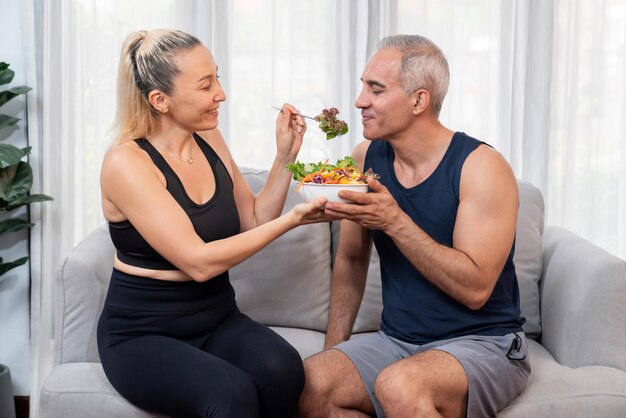 Gezond senior koppel in sportkleding met een kom fruit en groente Gezonde keukenvoeding en veganistische levensstijl voor fitness lichaamsbouw concept Slagkracht