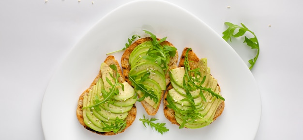 Gezond snackconcept. Toosts met avocado, garnalen en rucola op witte achtergrond. Bovenaanzicht, platliggend.