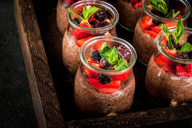 Gezond veganistisch ontbijt. Toetje. Alternatief eten. Pudding met chiazaad, verse aardbeien, bramen en munt. , in een oud houten dienblad. Weergave sluiten