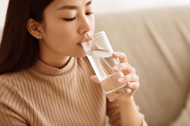 Gezond vloeibaar Aziatisch meisje dat schoon water drinkt uit een glasvrije ruimte