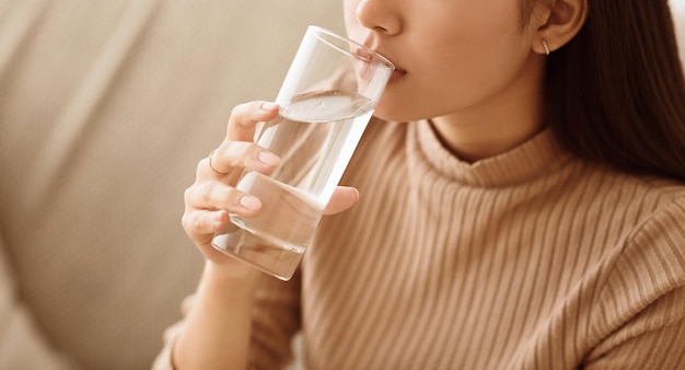 Gezond vloeibaar Aziatisch meisje dat schoon water drinkt uit een glasvrije ruimte