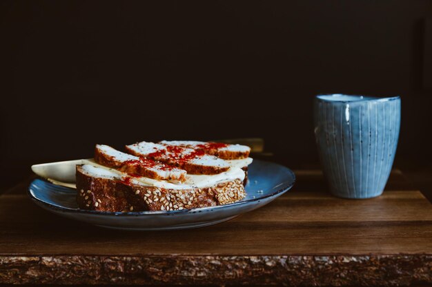 Gezond voedingsontbijt met espressokoffie en sandwich met kaas en kalkoenborst in een blauw bord geserveerd op een rustiek houten dienblad