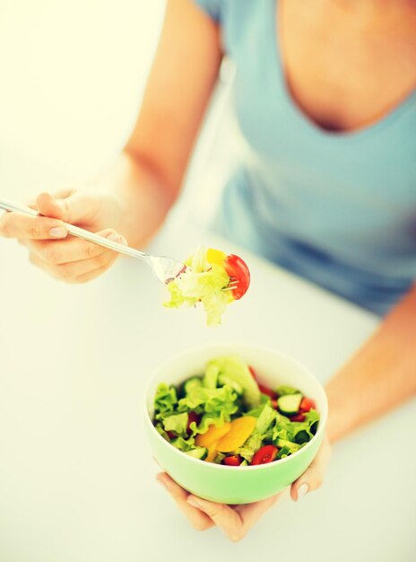 gezond voedsel en keukenconcept - vrouw die salade met groenten eet