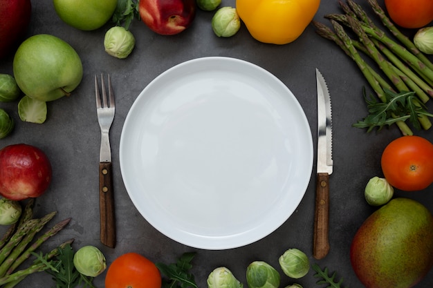 Gezond voedsel of dieetconcept. Lege ronde plaat met verschillende groenten en fruit rond. Plat leggen.